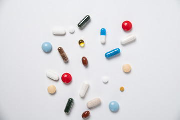 Multicolored medical pills and capsules on a white background, top view