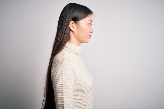 Young beautiful asian woman wearing casual sweater standing over isolated background looking to side, relax profile pose with natural face with confident smile.