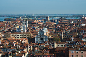Fototapeta na wymiar Top view of traditional buildings in the center of Venice. Skyline in the city, view of the red roofs from the tower. Warm autumn day while traveling in Europe. A romantic look. Blue sky with clouds.