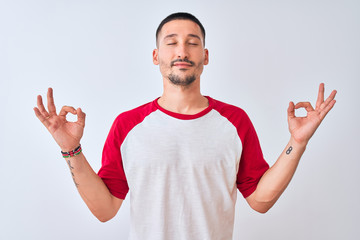 Young handsome man standing over isolated background relax and smiling with eyes closed doing meditation gesture with fingers. Yoga concept.