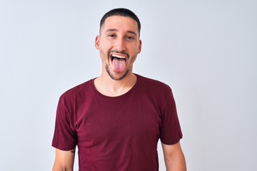 Young handsome man standing over isolated background sticking tongue out happy with funny expression. Emotion concept. © Krakenimages.com