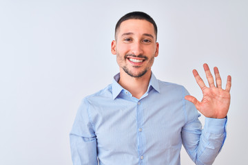 Young handsome business man standing over isolated background showing and pointing up with fingers number five while smiling confident and happy.