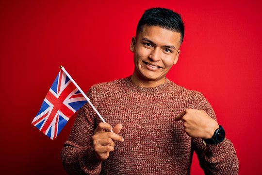 Young handsome latin patriotic man wearing united kingdom flag over red background with surprise face pointing finger to himself - Powered by Adobe