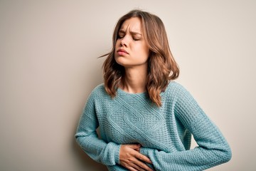 Young blonde girl wearing casual blue winter sweater over isolated background with hand on stomach...