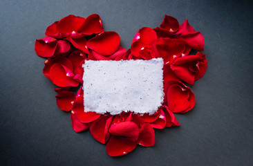 Beautiful frame of red rose petals with place for text. Handmade paper sheet, textured surface. Greeting card for the holiday.