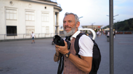 A Middle-Aged Man With A Backpack Admires The Beautiful View Of The City Preparing To Take A Picture.