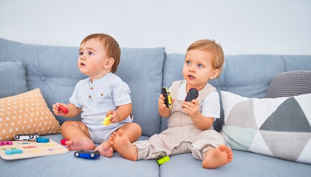 Beautiful toddlers sitting on the sofa playing with toys at home