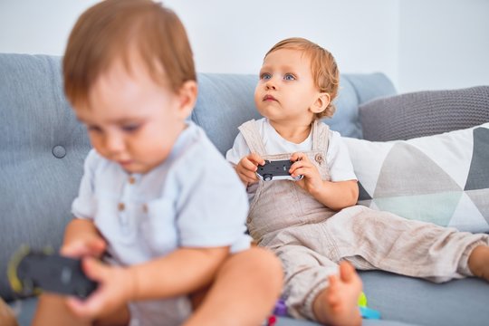 Beautiful toddlers sitting on the sofa playing with toys at home