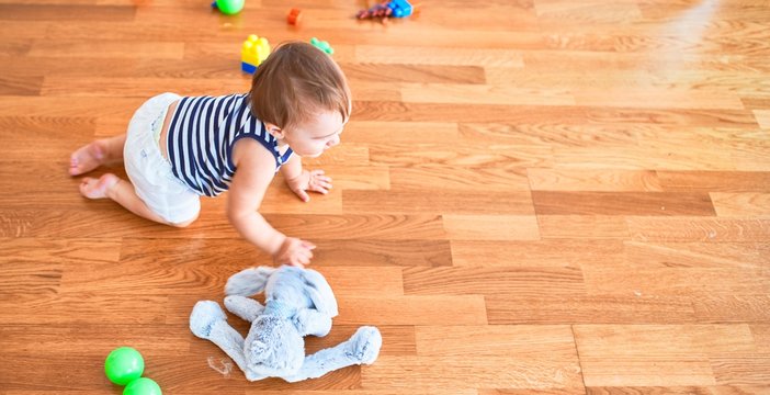 Adorable toddler crawling around lots of toys at kindergarten