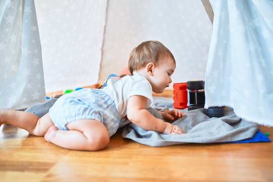 Adorable toddler crawling around lots of toys at kindergarten