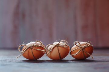 Easter beige eggs decorate with rope on brown wooden background