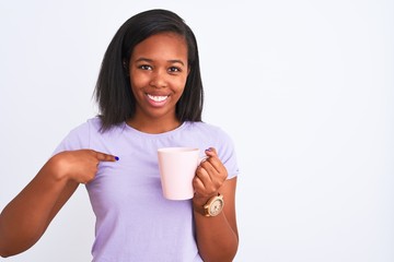 Young african american woman drinking a cup of coffee over isolated background with surprise face pointing finger to himself