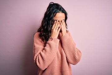 Young beautiful woman with curly hair wearing casual sweater over isolated pink background rubbing eyes for fatigue and headache, sleepy and tired expression. Vision problem