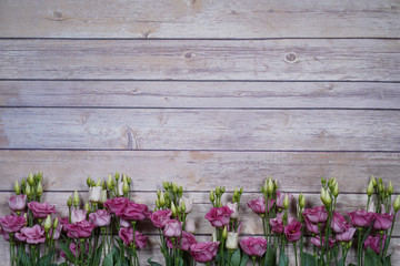 Fototapeta na wymiar purple and white eustom roses on wooden background. Empty space for design.