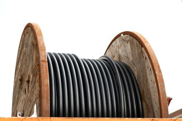 A wooden spool with black fiber optic cables
