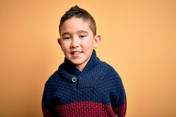 Young little boy kid wearing winter sweater over yellow isolated background with a happy and cool smile on face. Lucky person.