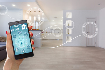 Smart home technology interface on smartphone app screen with augmented reality (AR) view of internet of things (IOT) connected objects in the apartment interior, person holding device