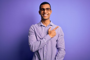 Handsome african american man wearing striped shirt and glasses over purple background cheerful with a smile on face pointing with hand and finger up to the side with happy and natural expression