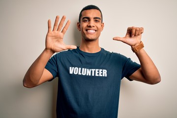 Young handsome african american man volunteering wearing t-shirt with volunteer message showing and...