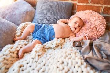 Adorable baby lying down on the sofa over blanket at home. Newborn relaxing and resting comfortable