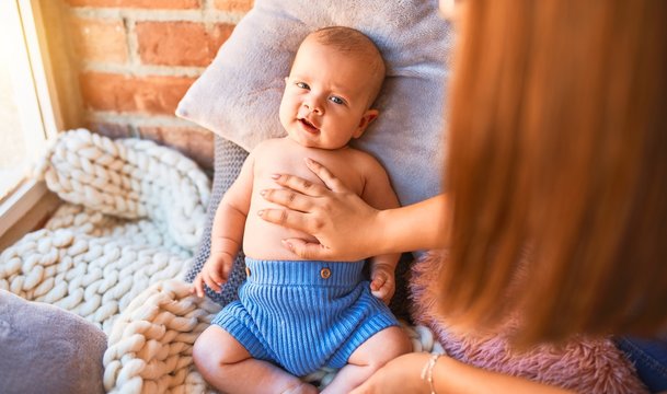 Young beautifull woman and her baby on the floor over blanket at home. Newborn and mother relaxing and resting comfortable