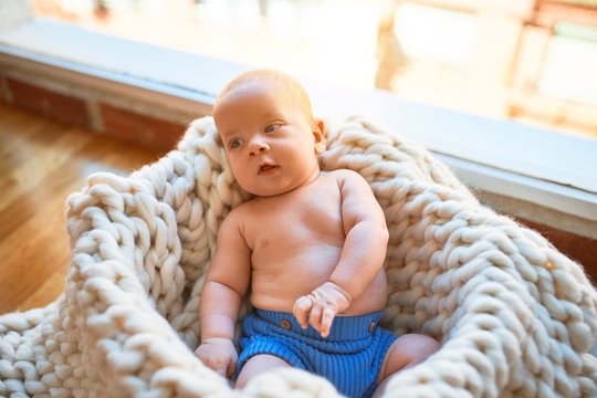 Adorable baby lying down on the floor over blanket at home. Newborn relaxing and resting comfortable
