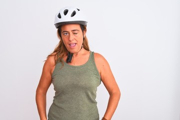 Middle age mature cyclist woman wearing safety helmet over isolated background winking looking at the camera with sexy expression, cheerful and happy face.