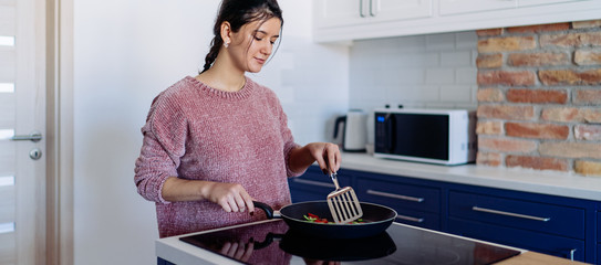 Woman frying vegetables the kitchen