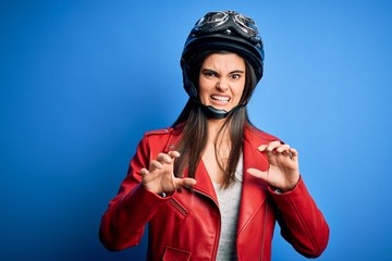 Young beautiful brunette motorcycliste woman wearing motorcycle helmet and jacket disgusted expression, displeased and fearful doing disgust face because aversion reaction. With hands raised