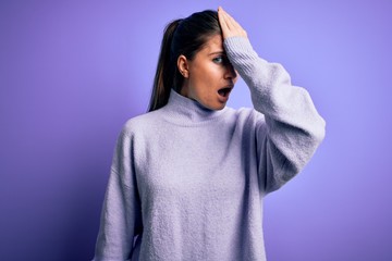 Young beautiful woman with blue eyes wearing casual turtleneck sweater over pink background surprised with hand on head for mistake, remember error. Forgot, bad memory concept.