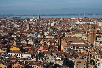 Fototapeta na wymiar Top view of traditional buildings in the center of Venice. Skyline in the city, view of the red roofs from the tower. Warm autumn day while traveling in Europe. A romantic look. Blue sky with clouds.