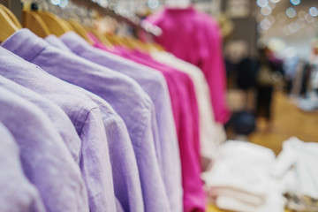 Modern fashion store. Buyers choose clothes. Shirts, hoodies, blouses and half-sweaters, a sweater on a hanger in a clothing store close-up. Sale and shopping in stores. Soft focus.