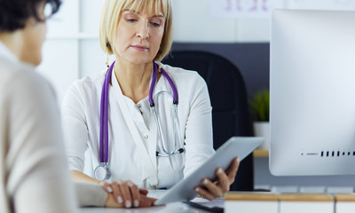 Female doctor using digital tablet talking with patients