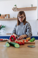 Young girl cutting paprika in the kitchen