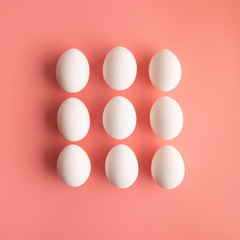 White chicken eggs in three rows shape rechtangle on minimalist pastel pink background. Abstract trendy Easter concept.