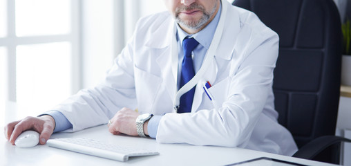 Portrait of senior doctor in office sitting at the desk