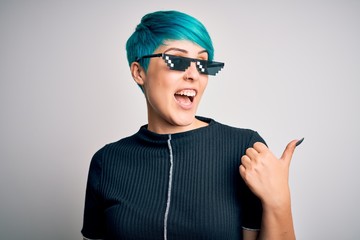 Young woman with blue fashion hair wearing thug life sunglasses over white background smiling with...