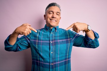Middle age handsome grey-haired man wearing casual shirt over isolated pink background looking...
