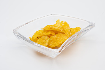 Fettige und ungesunde Kartoffelchips in einer Glasschale freigestellt vor weißem Hintergrund 