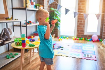 Young caucasian kid playing at kindergarten with toys. Preschooler boy happy at playroom.