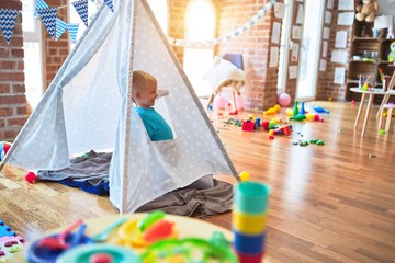 Young caucasian kid playing at kindergarten with toys. Preschooler boy happy at playroom.
