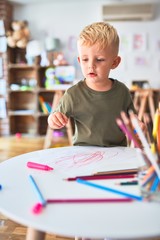 Young caucasian kid playing at kindergarten with toys. Preschooler boy happy at playroom.
