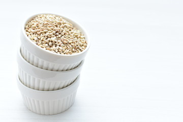Raw barley grains, released in containers on white wooden background