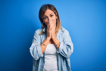 Middle age beautiful woman wearing casual shirt standing over isolated blue background laughing and...