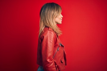 Fototapeta premium Middle age beautiful woman wearing casual jacket standing over isolated red background looking to side, relax profile pose with natural face with confident smile.