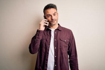 Young handsome man having conversation talking on the smartphone over white background with a...