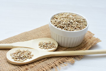 Raw barley grains, released in containers on white wooden background