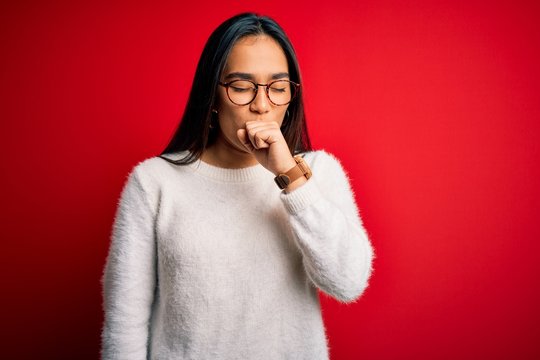 Young beautiful asian woman wearing casual sweater and glasses over red background feeling unwell and coughing as symptom for cold or bronchitis. Health care concept.