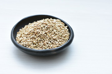 Raw barley grains, released in containers on white wooden background
