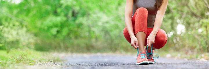 Exercise and sport running shoes runner woman tying laces getting ready for summer run in forest park panoramic banner header crop. Jogging girl exercise motivation heatlhy fit living. - obrazy, fototapety, plakaty